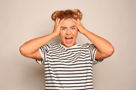 Portrait of irritated young woman on light background
