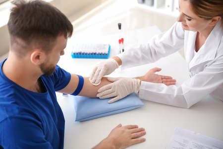 Female doctor preparing patient for blood draw in clinicの写真素材