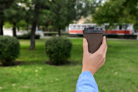 Woman holding paper coffee cup in parkの写真素材