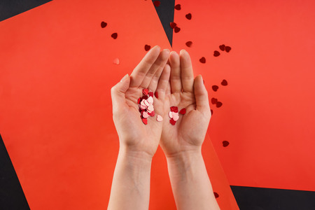 Female hands with decorative hearts on color background, top view