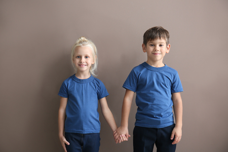 Boy and girl in t-shirts holding hands on color backgroundの写真素材