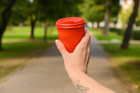 Woman holding paper coffee cup in parkの写真素材