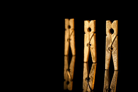 Golden clothes pins on black backgroundの写真素材