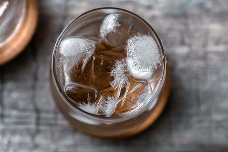 Glass of cold water and ice cubes on table, top view