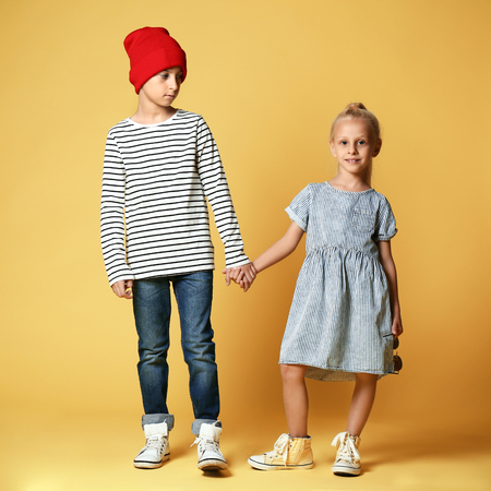 Cute boy and girl in fashionable clothes on color backgroundの写真素材