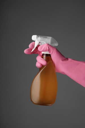 Woman holding spray bottle of detergent on grey backgroundの写真素材