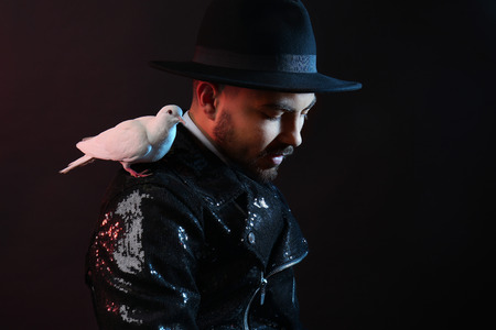 Male magician with white pigeon on dark backgroundの写真素材
