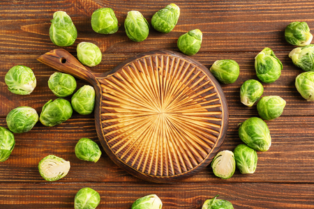 Fresh brussels sprouts and cutting board on wooden background, top viewの写真素材