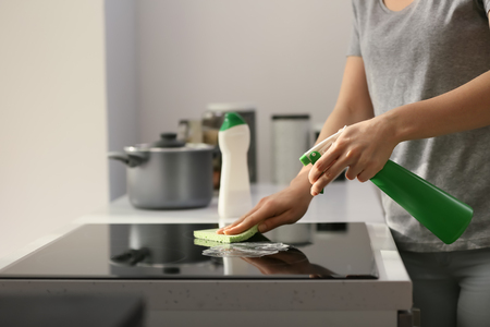Woman cleaning stove in kitchenの写真素材