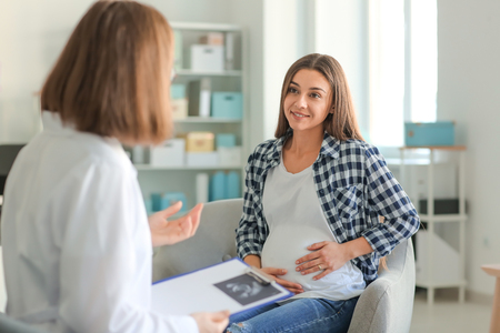 Young pregnant woman with her doctor in clinicの写真素材