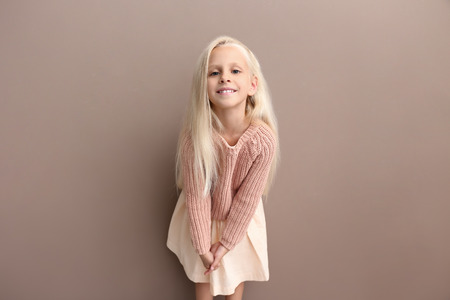 Cute girl in fashionable clothes on color backgroundの写真素材