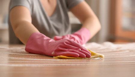Woman cleaning wooden table at home