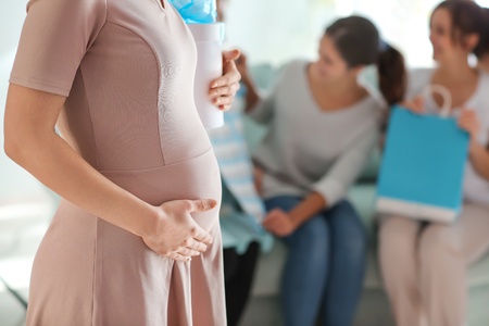 Beautiful pregnant woman with gift box at baby shower partyの写真素材