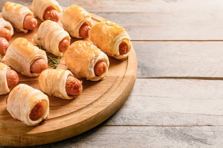 Fresh tasty sausage rolls on wooden boardの写真素材