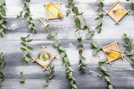 Flat lay composition with essential oil and eucalyptus branches on wooden backgroundの写真素材