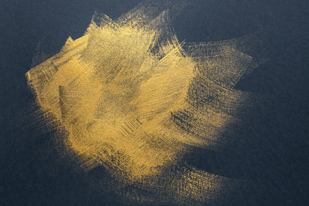 Strokes of gold paint on dark backgroundの写真素材