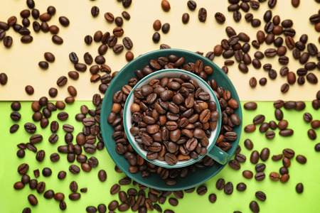Cup with coffee beans on color backgroundの写真素材