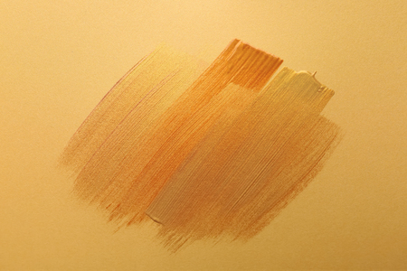 Strokes of different gold paints on color backgroundの写真素材