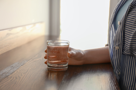 Woman with glass of fresh water at tableの写真素材