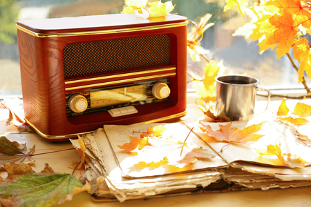 Old open book with retro radio and autumn leaves on windowsillの写真素材