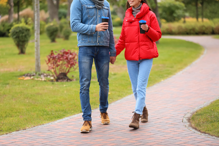 Loving young couple with coffee on romantic date in autumn parkの写真素材