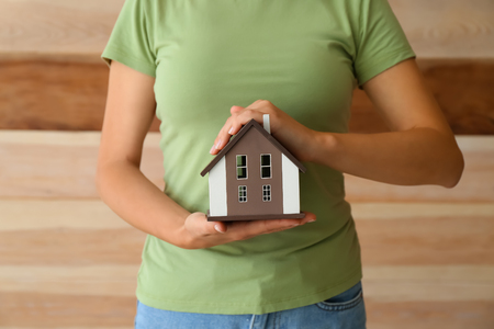 Woman with model of house on wooden background. Ecology conceptの写真素材