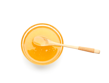 Bowl of honey with wooden spoon on white backgroundの写真素材
