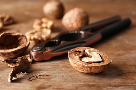 Half of walnut with shell and nutcracker on wooden tableの写真素材
