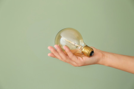 Female's hand with eco light bulb on color background