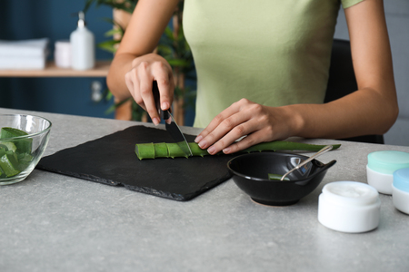 Woman cutting aloe leaf on slate plateの写真素材