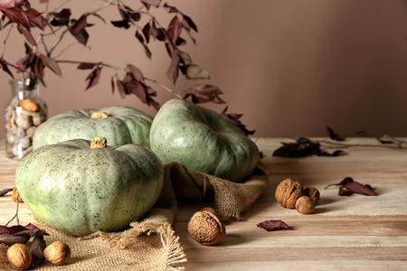 Whole fresh pumpkins with autumn leaves and walnuts on wooden tableの写真素材