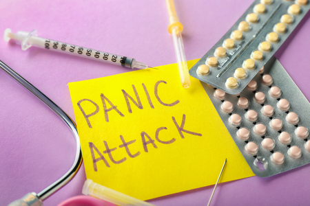 Sheet of paper with words PANIC ATTACK and medicines on color backgroundの写真素材
