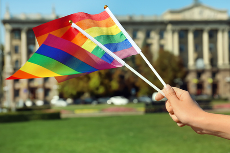 Woman holding rainbow LGBT flags outdoorsの写真素材
