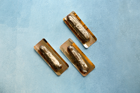 Tasty eclairs on color background