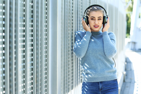 Beautiful young woman listening to music outdoorsの写真素材