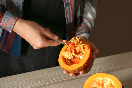Woman taking seeds out of ripe cut pumpkinの写真素材