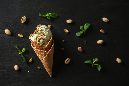 Waffle cone with delicious ice cream and pistachios on dark backgroundの写真素材