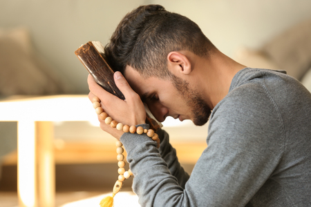 Young Muslim man with Koran praying at homeの写真素材