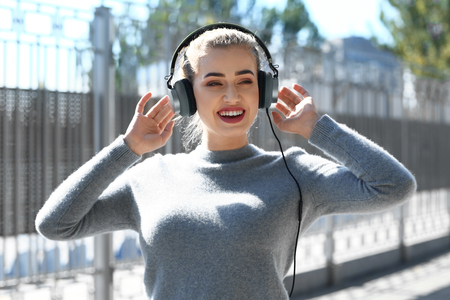 Beautiful young woman listening to music outdoorsの写真素材