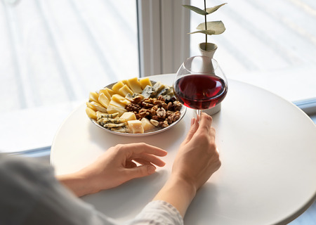 Woman with glass of wine and snacks in cafe
