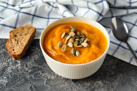 Bowl with tasty pumpkin cream soup on grey tableの写真素材