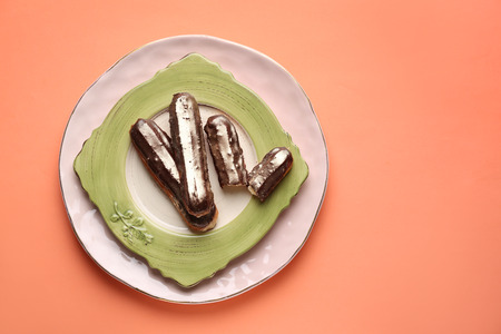 Plate with delicious eclairs on color background, top viewの写真素材