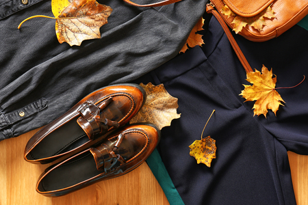 Stylish outfit with elegant shoes and autumn leaves on wooden background, top viewの写真素材