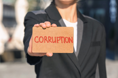Woman holding card with text STOP CORRUPTION outdoors, closeupの写真素材