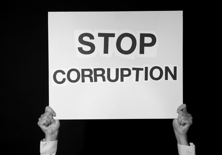 Woman holding placard with text STOP CORRUPTION on dark background, black and white effectの写真素材