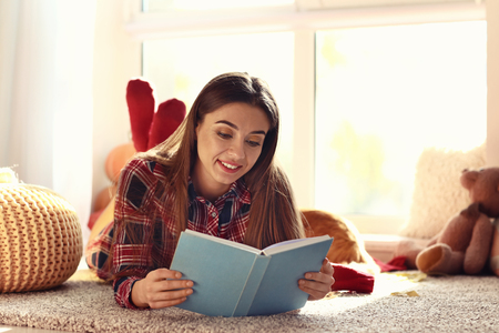 Woman reading book at home on autumn dayの写真素材
