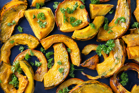 Tasty baked pumpkin pieces on dark table, top viewの写真素材