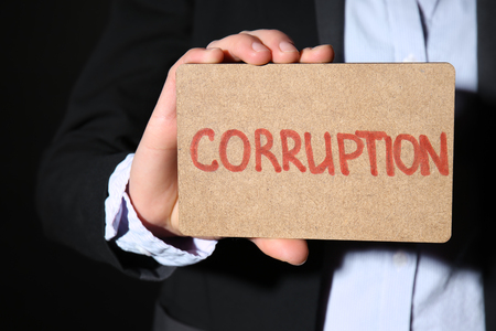 Woman holding card with text STOP CORRUPTION on black background, closeupの写真素材