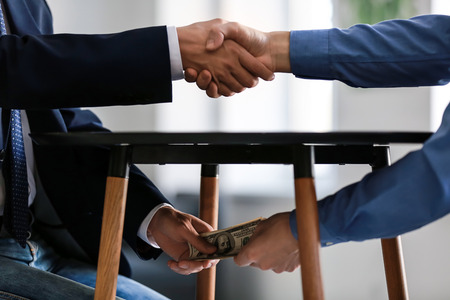 Businessman taking bribe from man under table. Corruption conceptの写真素材