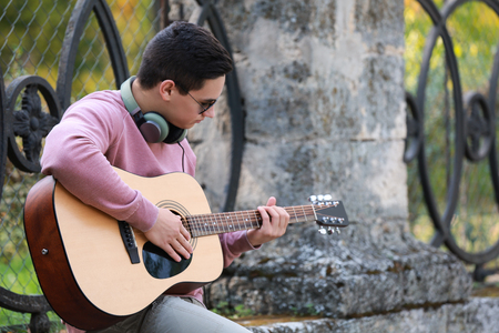 Young man playing guitar outdoorsの写真素材